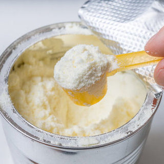 Hand holds scoop with newborn milk formula.