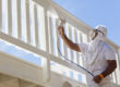 House Painter Wearing Facial Protection Spray Painting A Deck of A Home.