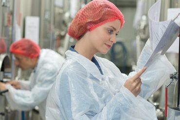 happy scientists posing checking paperwork in factory