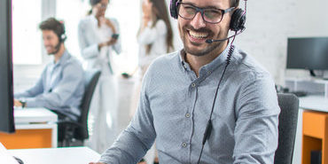 Happy young male customer support executive working in office. Happy young male customer support executive working in office.