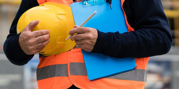 construction worker with orange safety vest holding a yellow helmet construction worker with orange safety vest holding a yellow helmet